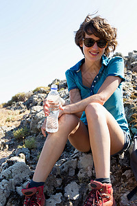 坐在岩石上喝水的女性高清图片