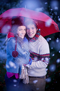 雪中雨伞下微笑的情侣高清图片