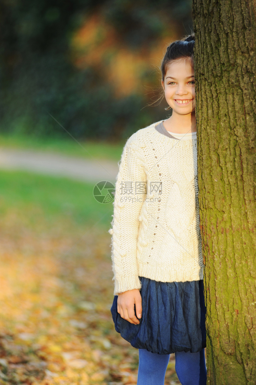 微笑的女孩站在树旁图片
