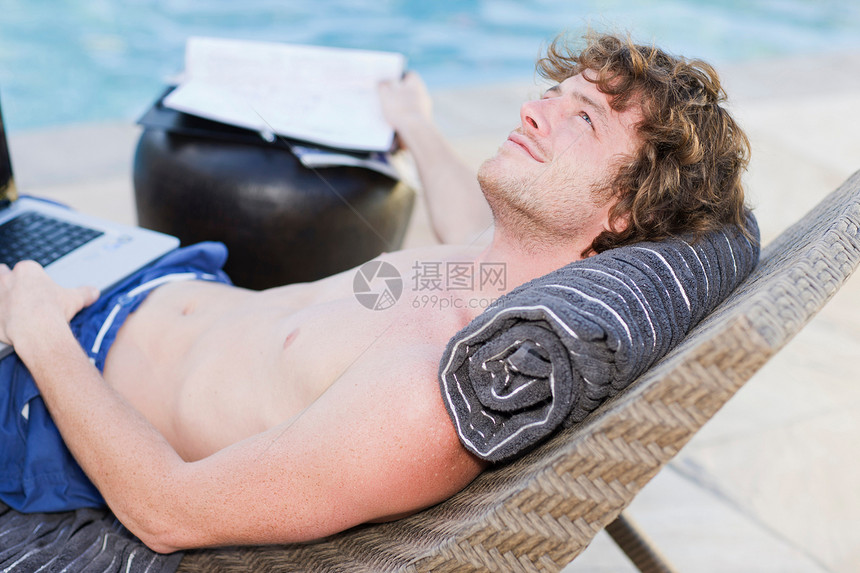 躺在沙滩椅上用电脑的男人图片
