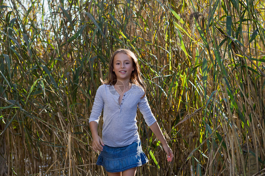 微笑的女孩在芦苇中行走图片