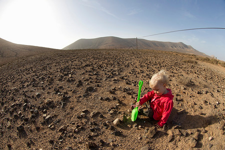 在沙漠中玩铁铲的小男孩图片