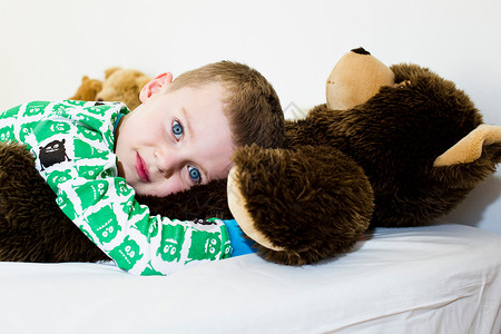 男孩在床上拥抱泰迪熊图片