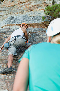 男人攀爬陡峭的岩石图片