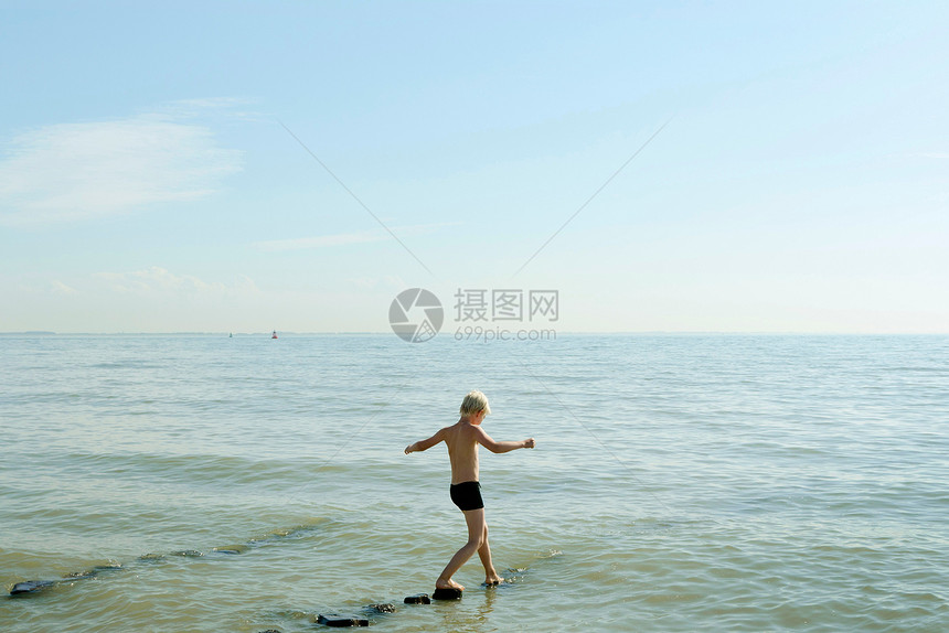 男孩在海滩碎石上行走图片