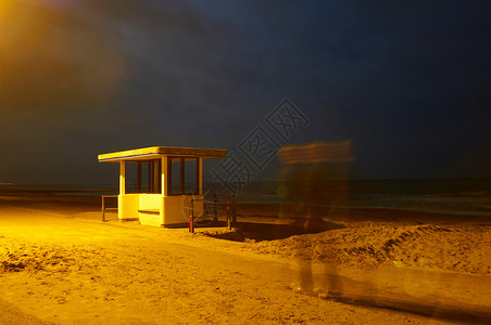 夜间海滩上模糊的人影和亭子图片