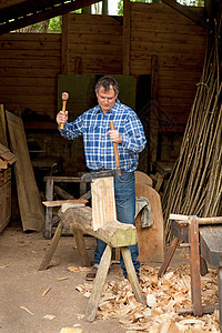 店铺中年长男子在雕刻木头图片