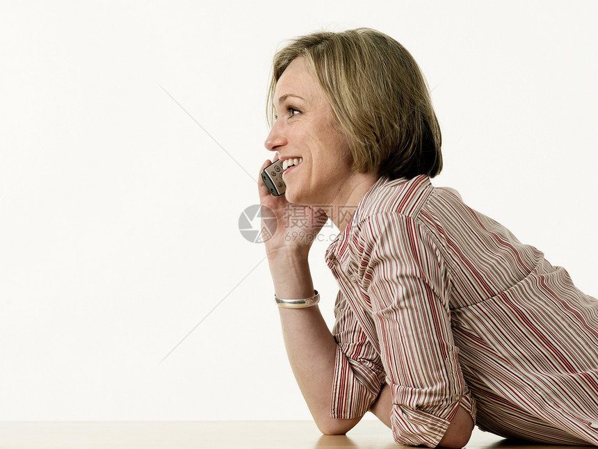 微笑的妇女通过电话交谈图片