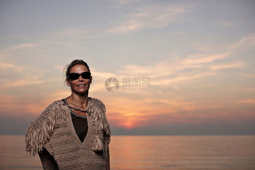 日落时妇女站在海滩上图片