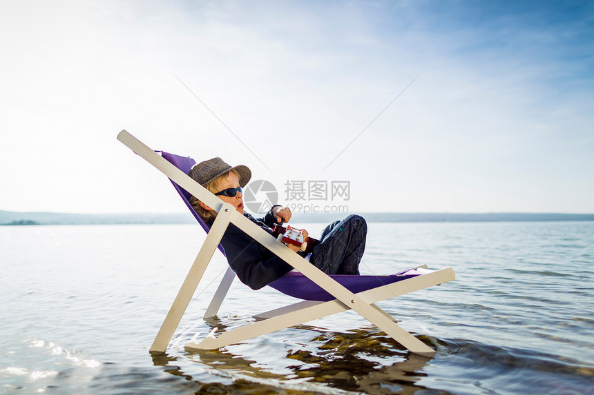 小男孩在湖边躺椅上休息图片
