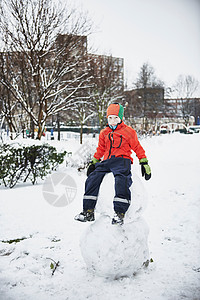 男孩坐在公园的雪人上背景图片