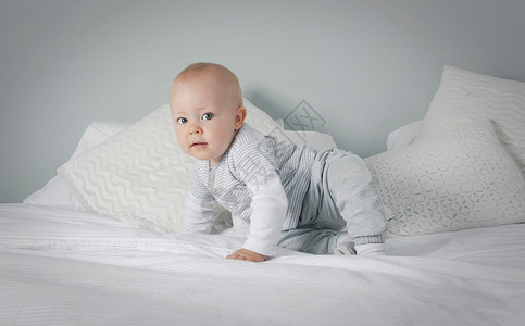 婴儿男孩在床上爬行背景图片