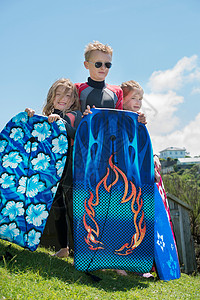 身穿湿衣拿着冲浪板的儿童背景图片