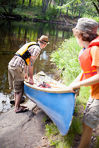 父亲和儿子在河里推独木舟图片