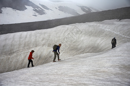 小团体家庭在雪山坡上徒步背景