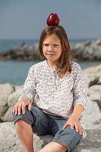 女孩在海边石头上顶着苹果图片