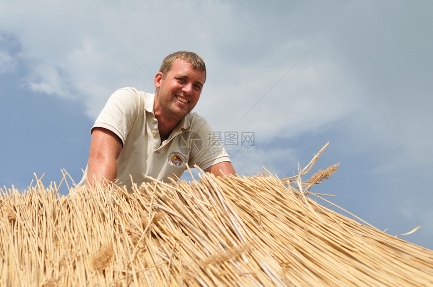 在稻草屋顶工作的人图片