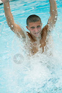 男孩从游泳池里跃出水面图片