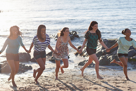 多名女性在海滩上手牵手奔跑图片