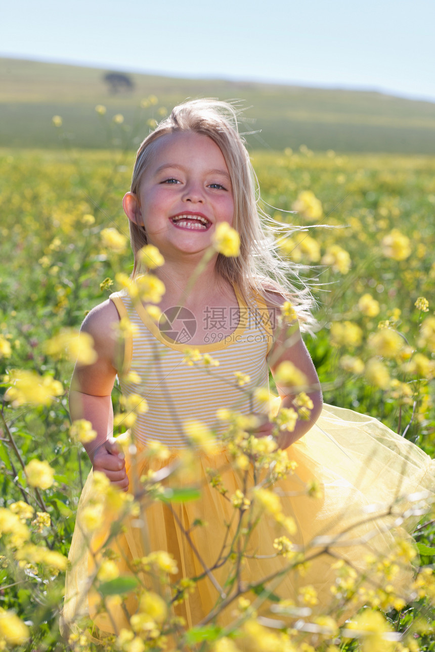 微笑的女孩在鲜花田里玩耍图片