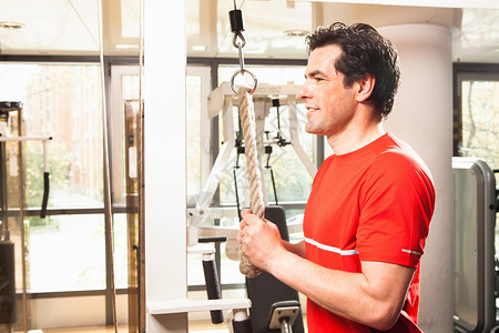 男子在健身房使用运动设备图片