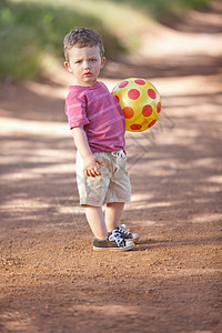 在泥土路上打球的男孩图片