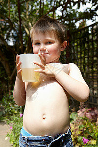 男孩子在花园里喝果汁图片
