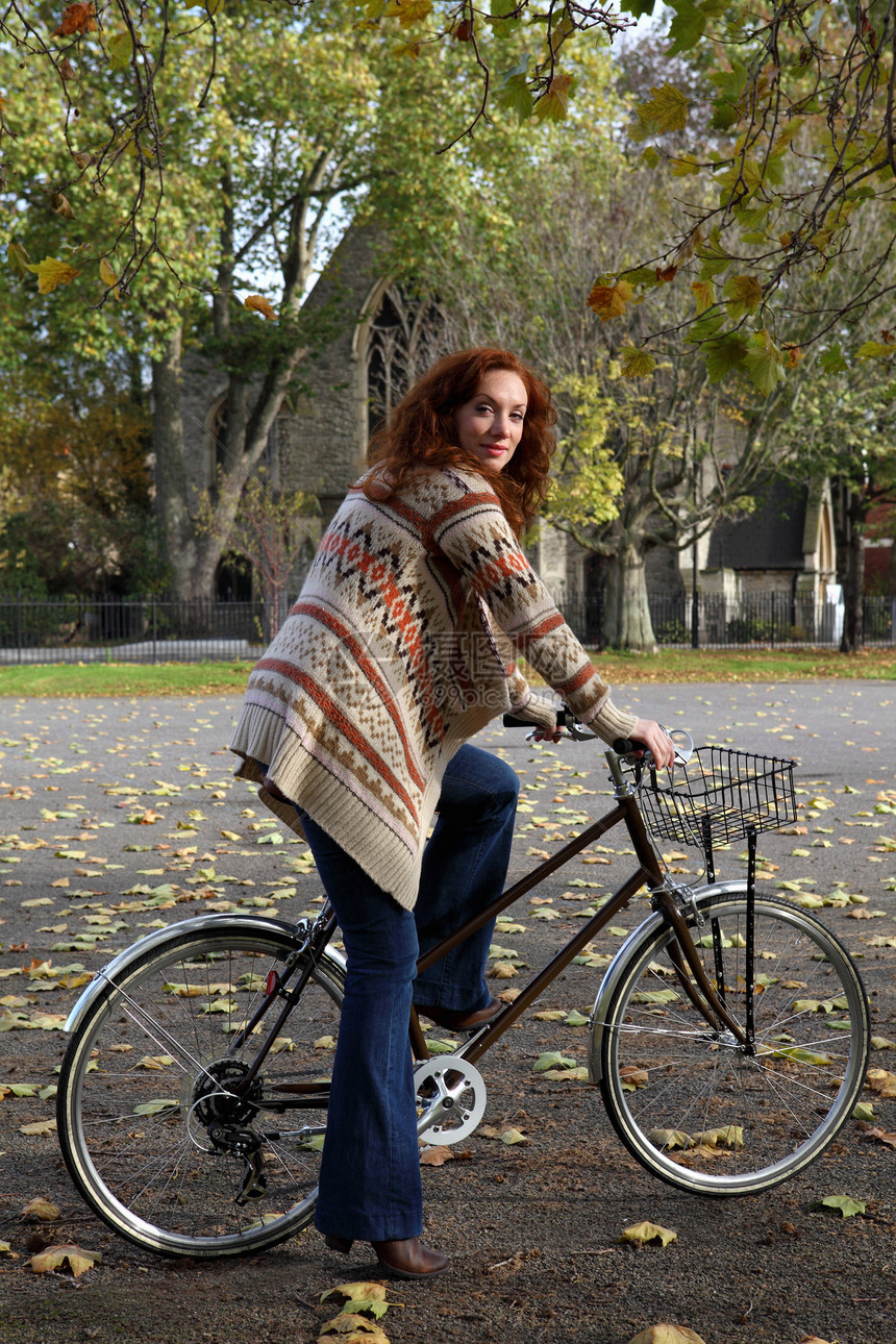 妇女站在公园的自行车上图片