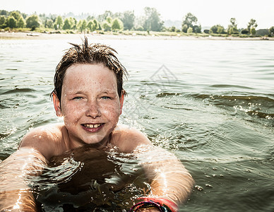 微笑的男孩在湖中游泳图片