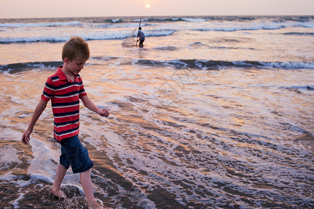 男孩在海边的浪中行走图片