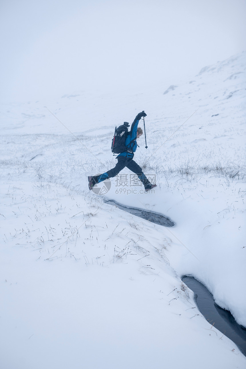 在雪地上跳跃的登山者图片