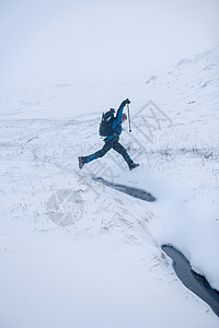 在雪地上跳跃的登山者图片
