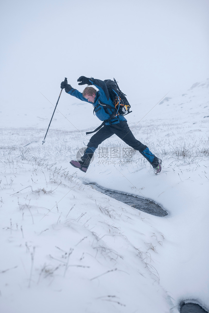 在雪地上跳跃的登山者图片