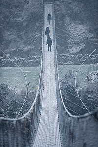 人走在覆盖雪的吊桥上图片