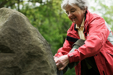 老年妇女在公园的岩石上绑鞋图片