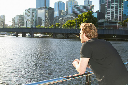 在桥上看城市河流风景的男子图片