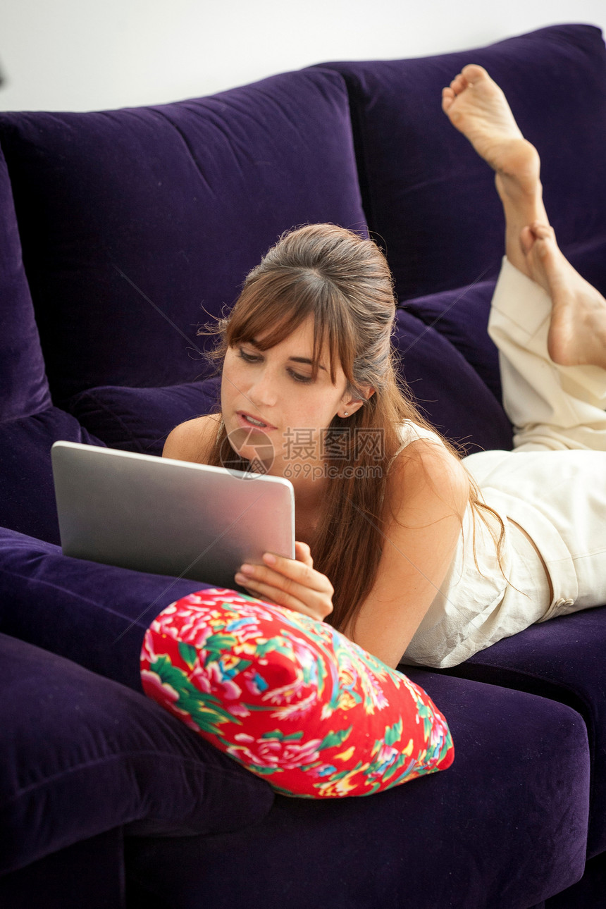 在沙发上使用平板电脑的女性图片