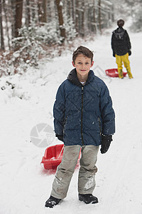 男孩在雪坡上拉雪橇图片