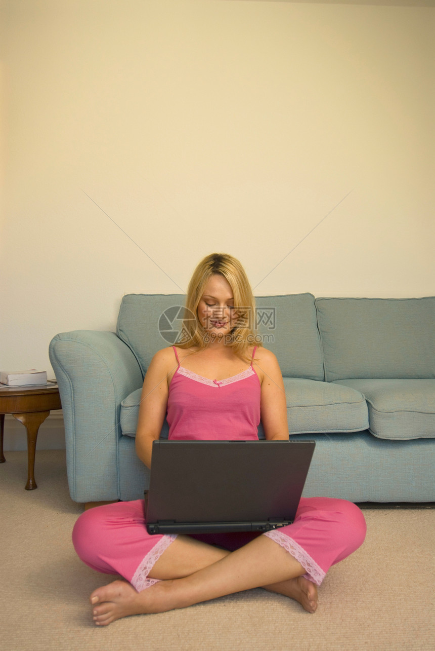 妇女在地板上使用笔记本电脑图片
