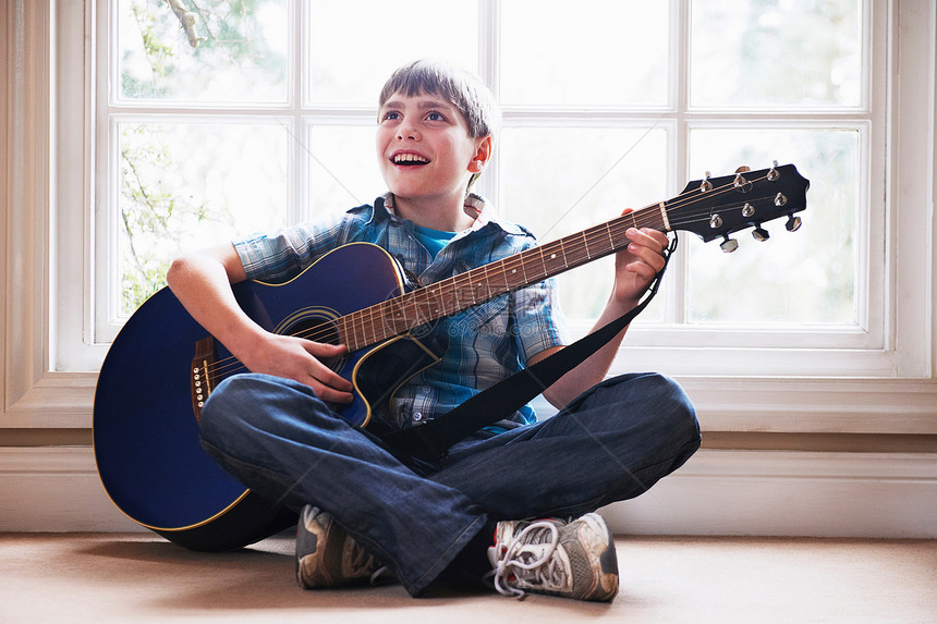 男孩在地板上弹吉他图片