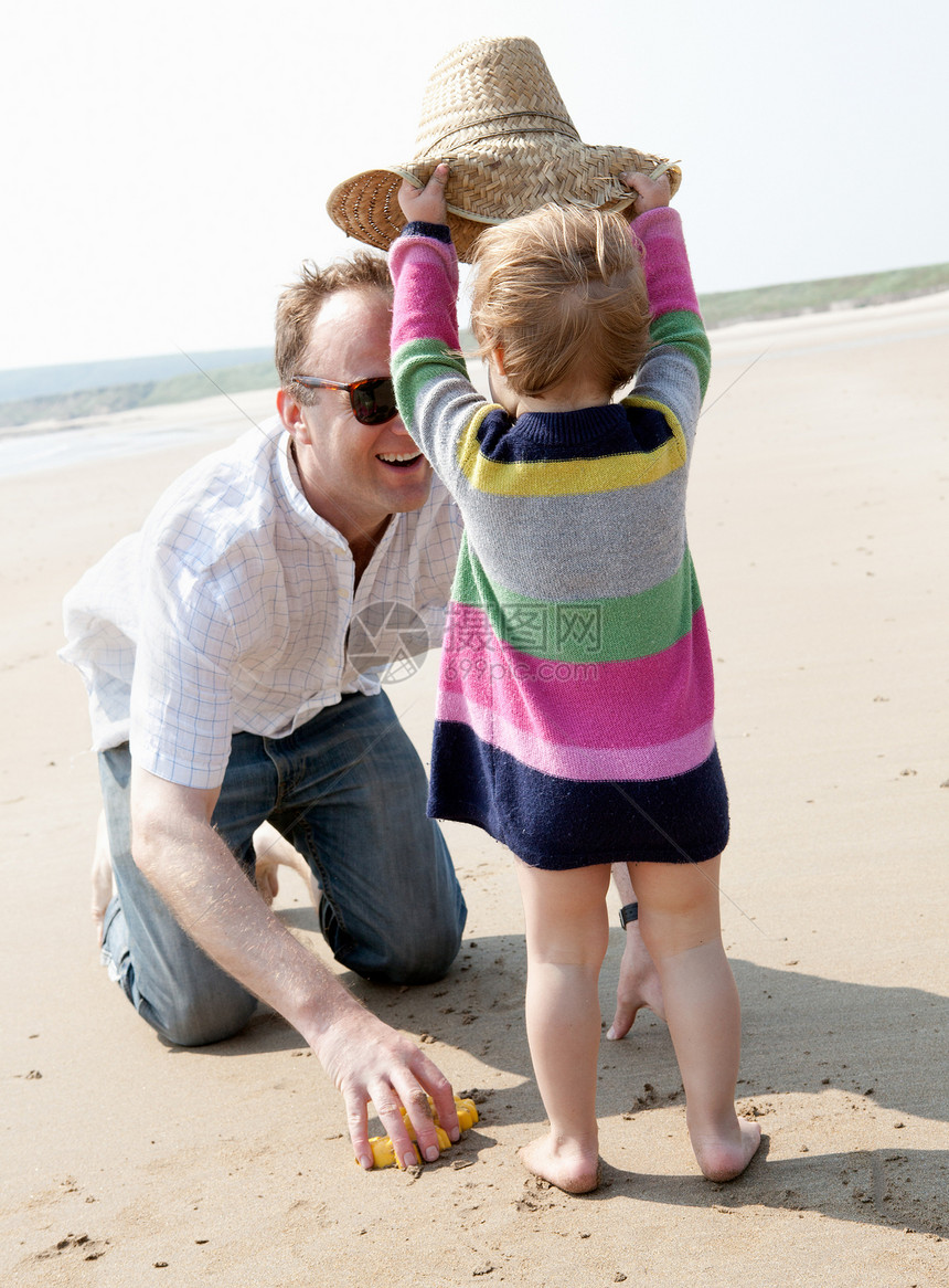 女孩在海滩上给父亲戴帽子图片