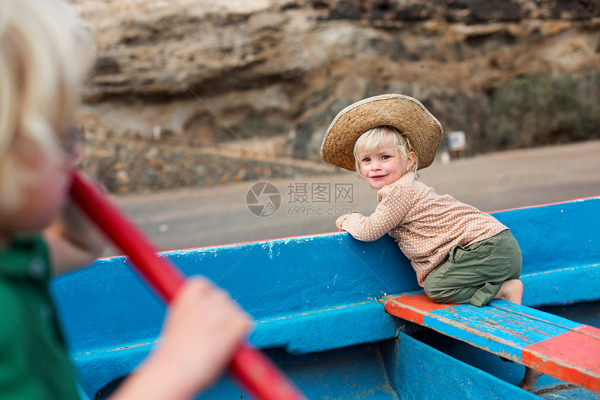坐在海滩上船的女孩图片