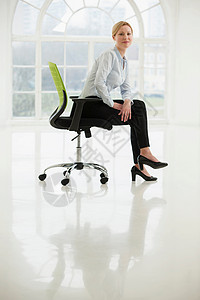 坐在办公椅上的女商人图片