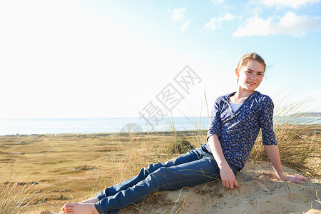 泽西岛辖区坐在沙滩上的少女在微笑背景