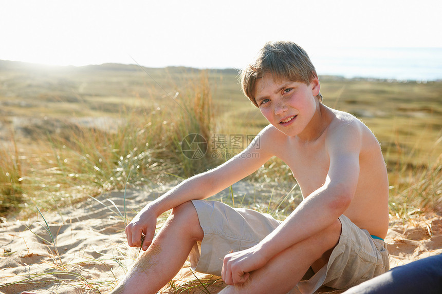 男孩坐在海滩上图片