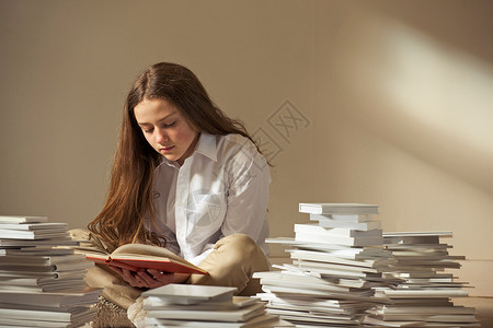 女孩坐在满是书的地板上阅读图片