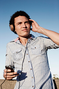 年轻人在用耳机听音乐背景图片