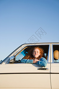 一位年轻女士从车窗向外看背景图片