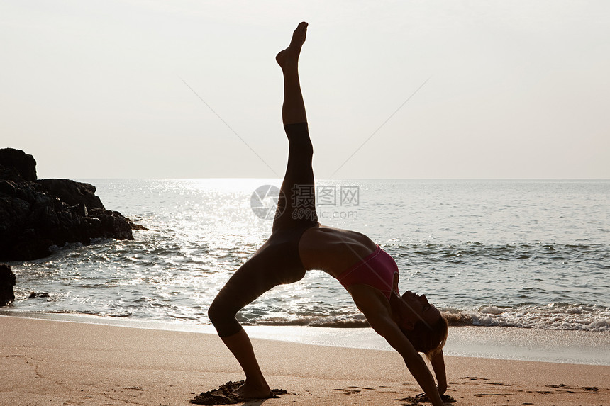 日落时在海滩上做瑜伽的女人图片