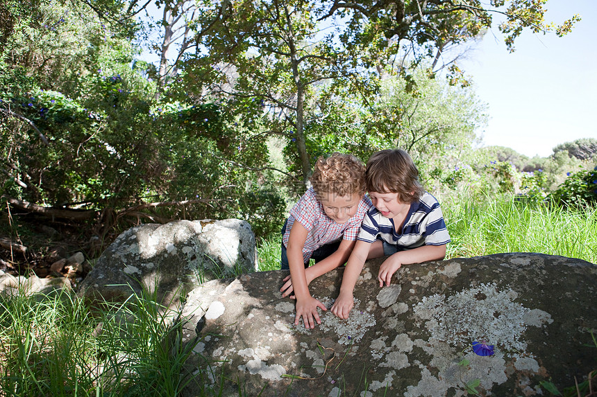 两个男孩靠在岩石上图片